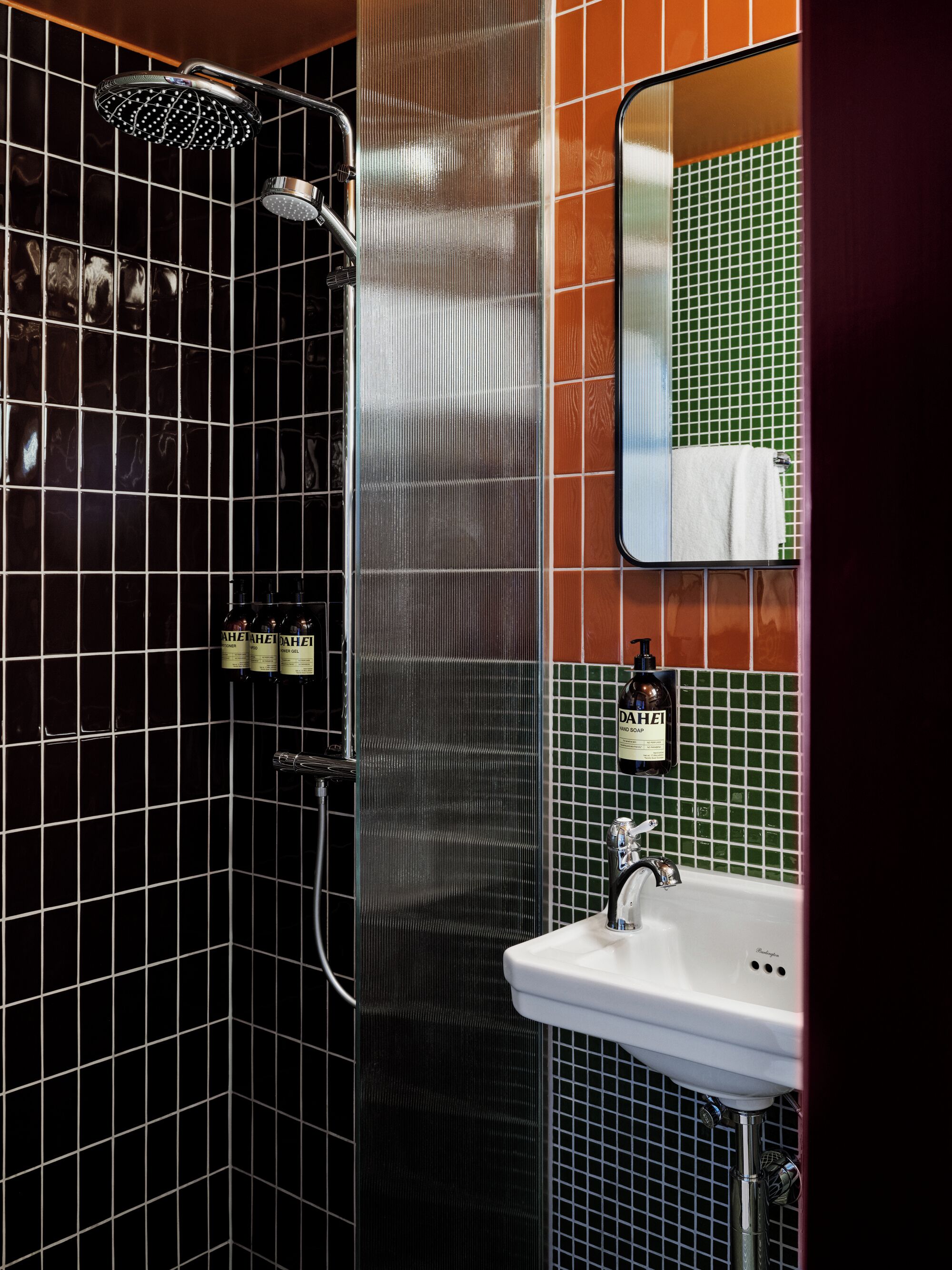 A bathroom with a shower, a sink, and toiletries.