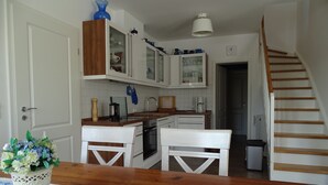 Une cuisine avec des meubles blancs, un plan de travail en bois et un coin repas comprenant une table et des chaises.