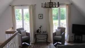 Une pièce comprenant deux fauteuils, un canapé, une table avec des bougies et un téléviseur.