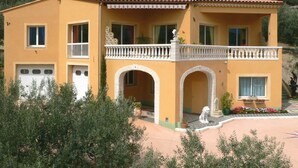 Ein zweistöckiges Gebäude mit Balkon, Garage und einer Statue im Innenhof.