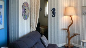 Ein Wohnzimmer mit einem blauen Sofa, einer Holzbodenlampe und gestreifter Tapete.