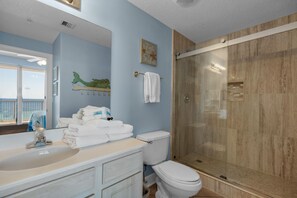 Un baño con lavamanos, espejo y ducha con mampara de vidrio.