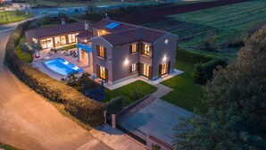 Una casa moderna de dos plantas con piscina, ventanas amplias y césped bien cuidado.