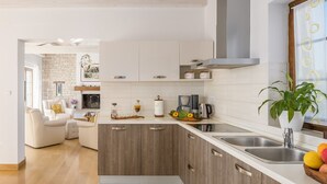 Cocina moderna con armarios de madera, estufa integrada y un ventanal con una planta.