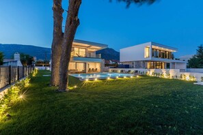 A modern two-story house with a swimming pool, surrounded by a well-maintained lawn and a tree. - Luxury Seafront Villa Papillon Split with Pool (Kaštel Kambelovac)