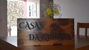 Une enseigne en bois portant l’inscription « CASAS DA RIBETRA » est posée sur une table.
