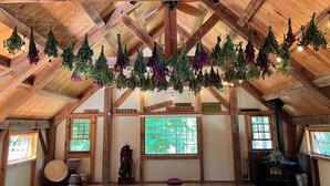A spacious attic room with wooden beams, hanging plants, and a large window. - The Farmhouse At Shilo Farm, 4 miles from Portsmouth, 10 minutes from the Beach (Eliot)