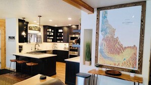 Een moderne keuken met een centraal eiland, barstoelen en een grote inlijste kaart aan de muur.