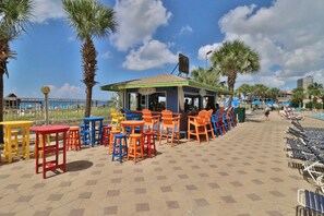 Relax in a tranquil outdoor seating area surrounded by palm trees and hexagonal tiles.