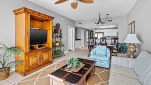 A spacious living room with a large wooden entertainment center, a television, and a ceiling fan. - 3BR 2BA in tower 2 @ The Calypso, Closest Complex to Pier Park! (Panama City Beach)