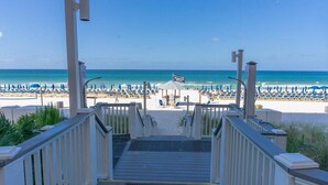 A beach view with a staircase leading to the beach, umbrellas, and a flag. - 3BR 2BA in tower 2 @ The Calypso, Closest Complex to Pier Park! (Panama City Beach)