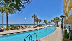 A pool area with lounge chairs and palm trees, overlooking a beach. - 3BR 2BA in tower 2 @ The Calypso, Closest Complex to Pier Park! (Panama City Beach)