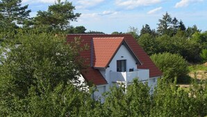 A house with a red roof, white exterior walls, and a small balcony. - thatched house, direct sea view, idyllic location in vacation region Usedom (Freest, Usedom)