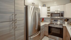 A modern kitchen with stainless steel appliances, wooden cabinets, and a tiled backsplash. - Tropical Paradise Beach Getaway, Villa #4 (Lauderdale-by-the-Sea)