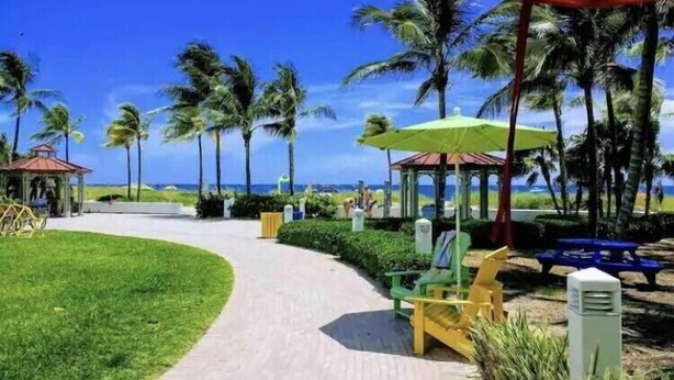 A pathway leading to beach umbrellas and palm trees. - Beach Getaway, Cozy Studio Villa #2 (Lauderdale-by-the-Sea)