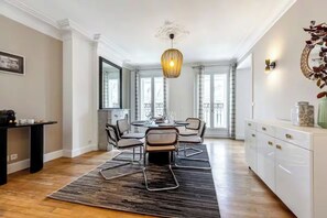 A modern dining area with a round table, chairs, and a patterned rug.
