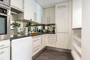 A modern kitchen with white cabinets, stainless steel appliances, and a black countertop.