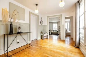 A modern interior with a wooden floor, a console table, and a large mirror.