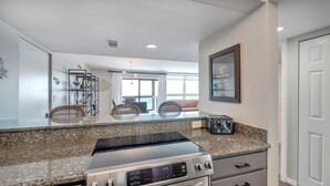 Eine moderne Küche mit Granit-Arbeitsplatten, einem Edelstahlherd und einem eingebauten Backofen.