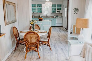 Un coin repas avec des chaises en osier, une table ronde et un vase de fleurs.