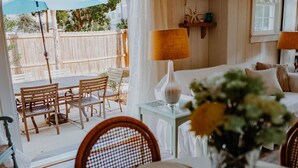 Ein gemütliches Zimmer mit einem Bett, einem Tisch gedeckt mit Geschirr und Blick auf eine Holzterrasse.
