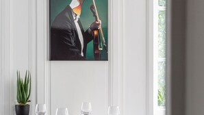 Ein Essbereich mit einem Tisch für vier Personen, einem Blumentopf und einem gerahmten Kunstwerk an der Wand.
