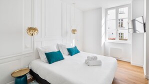 Ein Hotelzimmer mit einem großen Bett, weißen Wänden, einem Fenster mit Aussicht und einem kleinen runden Tisch.