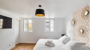 A bedroom with a bed, a black pendant light, and a window with a view of trees. - Neruda - Le 31 bis - Appt proche centre Rennes (Rennes)