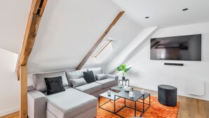 Una sala de estar moderna con un sofá seccional gris, una mesa de centro negra y un televisor grande en la pared.