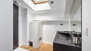 Une cuisine moderne dotée d’une verrière, d’un lave-vaisselle encastré et d’un plan de travail noir agrémenté d’appareils électroménagers en acier inoxydable.