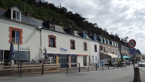 Eine Straße mit Gebäuden, darunter ein Restaurant namens 'Ty Papa' und ein Schild für 'Au Phare d'Erquy'.