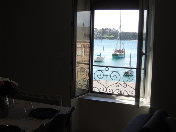A room with a window overlooking a harbor with sailboats.