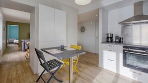 Eine moderne Küche mit weißen Schränken, einer Edelstahl-Dunstabzugshaube und einem Essbereich mit Tisch und Stühlen.