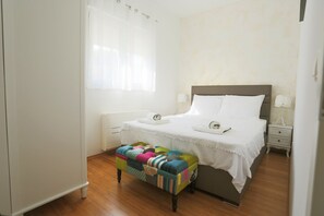 A neatly arranged bedroom with a bed, bedside tables, a bench, and a window with curtains.