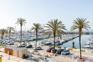 A marina with numerous boats docked, palm trees lining the area, and cars parked along the roadside. - A&n   Seaport     1a (Caleta de velez)