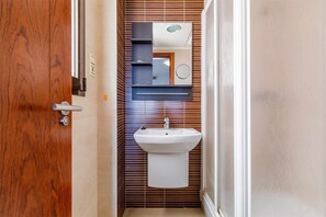 A bathroom with a wooden door, a white sink, and a mirror above it.