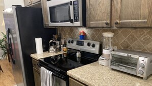 Eine Küche mit Kühlschrank, Mikrowelle, Herd, Backofen, Toaster und Mixer.