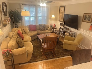 A living room with a sectional sofa, a wooden coffee table, a TV, and a fireplace.