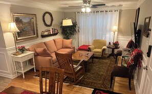 A living room with a sofa, armchairs, a coffee table, and a dining table. There are lamps, a plant, and a bookshelf with books. - Spacious 3 bed 2 bath condo close to Memorial Park, Five-points, & UGA in Athens (Athens)