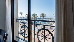 Ein Balkon mit Blick auf einen Yachthafen, Palmen und einen klaren Himmel.