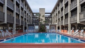 En swimmingpool med liggestole og en plantekasse i midten.