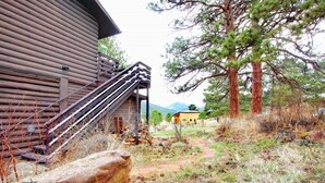 A rustic log cabin with a wooden staircase leading to a deck, surrounded by trees and a mountain in the background. - Gorgeous Views, RMNP, Close to Downtown Estes Park, Real Log Cabin- Longs Peak Cabin (Estes Park)