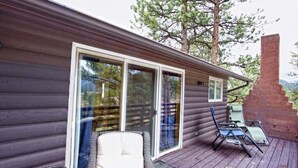 A wooden cabin with a deck, sliding glass doors, and outdoor seating. - Gorgeous Views, RMNP, Close to Downtown Estes Park, Real Log Cabin- Longs Peak Cabin (Estes Park)