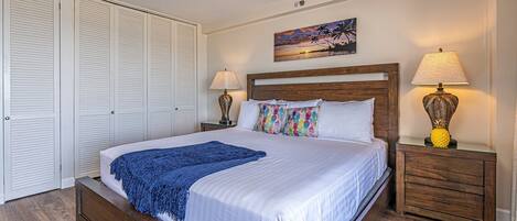 A neatly made bed with a blue throw blanket, wooden headboard, and two bedside lamps.