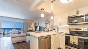 A modern kitchen with a central island, stainless steel appliances, and a view to the outside.
