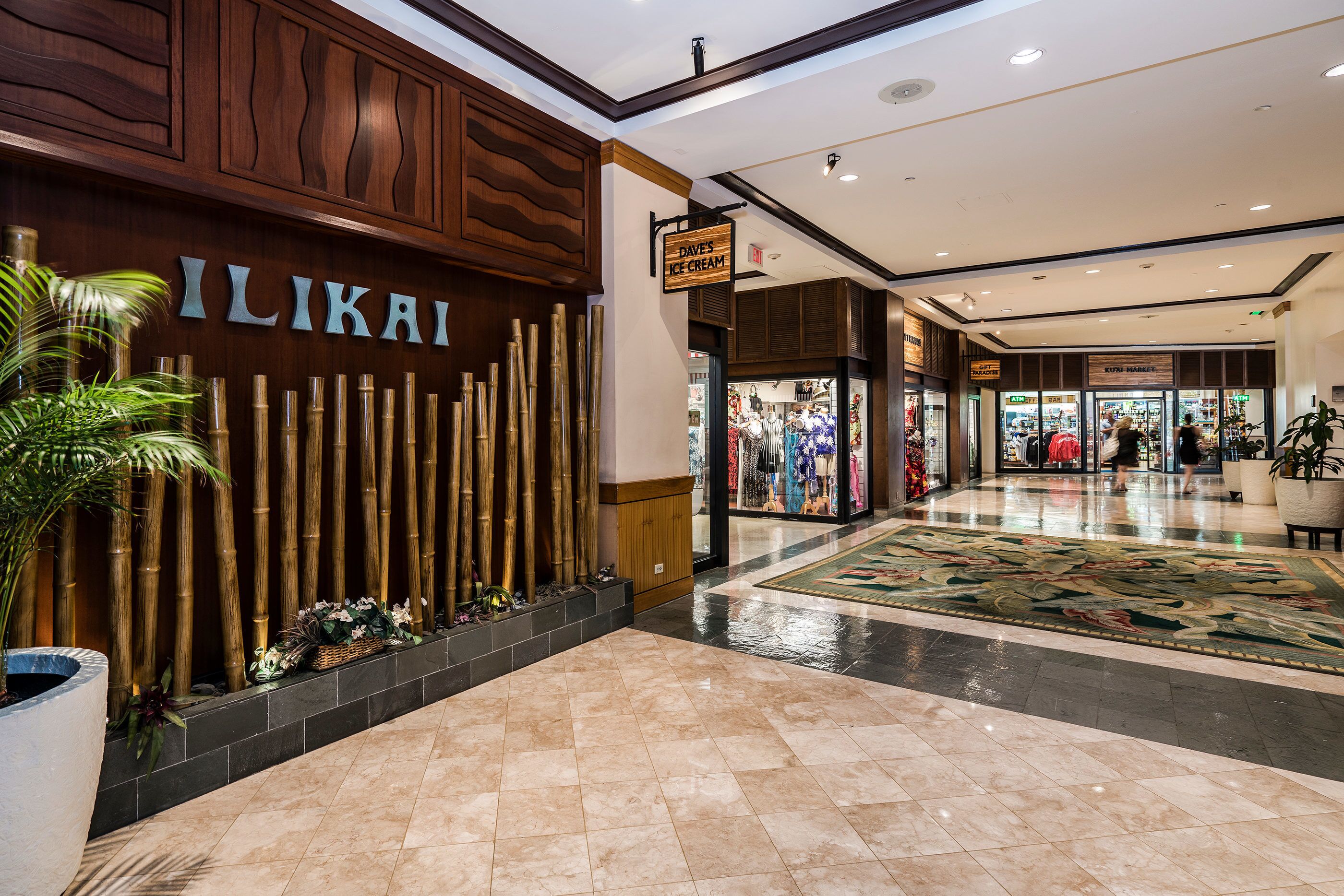 A modern interior with a bamboo wall, a sign for 'ILIKAI', and a tiled floor.