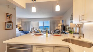 A modern kitchen with a large island, stainless steel appliances, and pendant lighting.