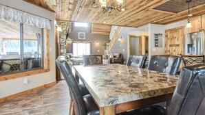 Un comedor con una gran mesa de madera y sillas de cuero, una pared de piedra y un techo de madera con vigas a la vista.
