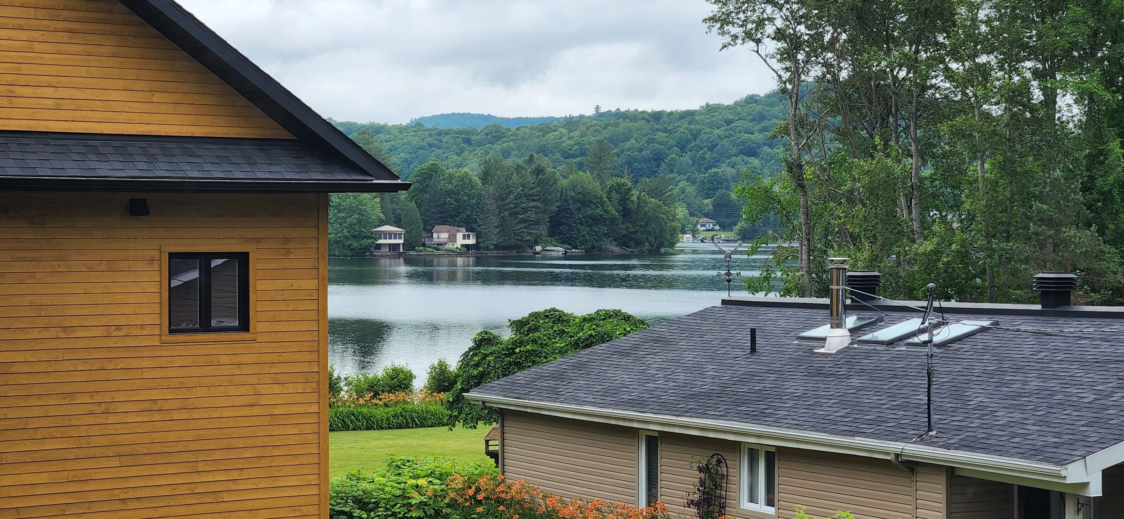 A lakeside view with a wooden house and a smaller building across the water.