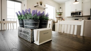 A kitchen with a wooden table, potted lavender plants, and a napkin holder labeled "FARM HOUSE LOCAL." - Farmhouse at Lincoln Suites — Smart Home, King Bed, Sheridan WY (Sheridan)